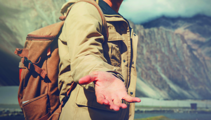 Young travel man lending a helping hand in outdoor mountain scenery