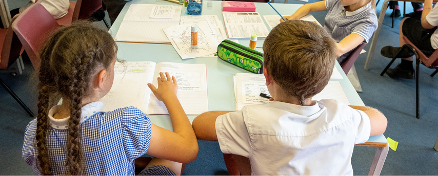 Children at classroom table with their work books